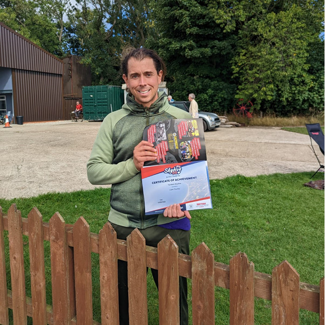 Liam holds up a copy of his skydive certificate