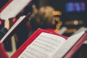 A red music book with sheet music in. Out of focus fairy lights in the background.