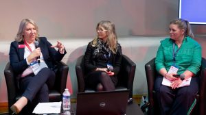 Three women sat down holding microphones