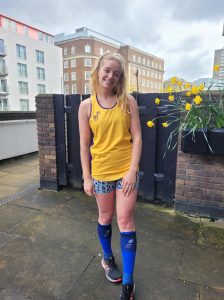 Madeleine stood outside dressed in running clothes including her Hft branded running vest