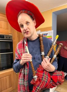 A man wearing a red hat holding the bagpipes