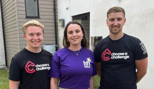 Two men wearing black t-shirts that read 'Choose a Challenge' and a woman wearing a purple t-shirt that reads 'Hft'