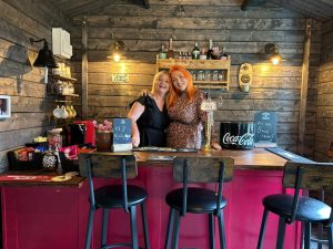 A photo of two women standing behind a bar.