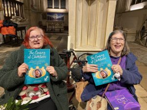 Two women holding blue programmes that read 'The Coming of Christmas'
