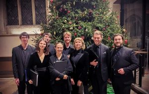 The Donaghue Consort all dressed in black in front of a Christmas tree