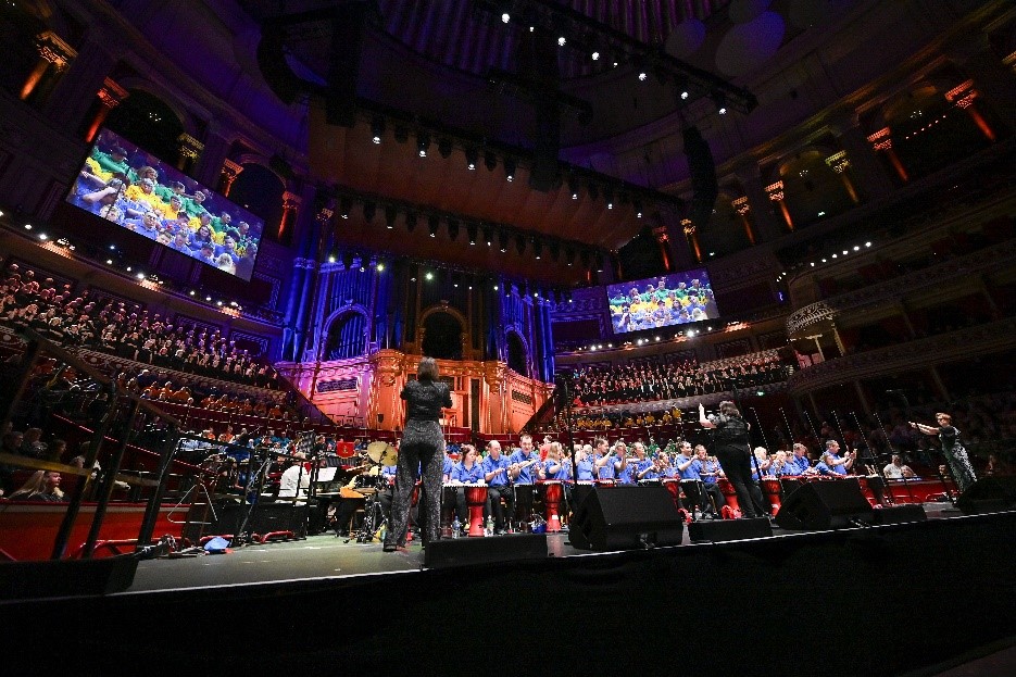 A view of the stage, with the conductor and the orchestra, with the audience behind.