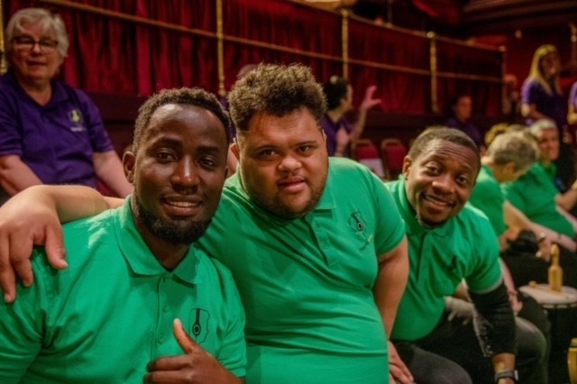 Group of people smiling at the camera, sitting in the theatre.