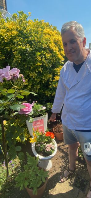Lawrence is pictured in the garden with his 'toilet planter' filled with bright flowers.