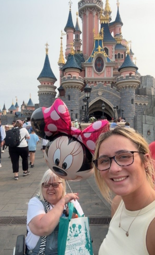 Marianne at Disneyland holding a Minnie Mouse Balloon, and Support Worker Lauren.