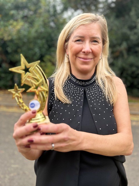 Helen holding her trophy which features three gold shooting stars.