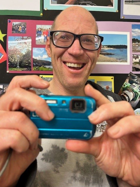 Colin, one of the photographers, holding his blue digital camera.